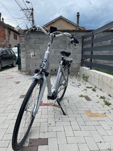 bicikli sa prednjim i zadnjim amortizerima: Električni bicikl u srebrnoj boji. Poseduje crno sedište i bateriju — 10