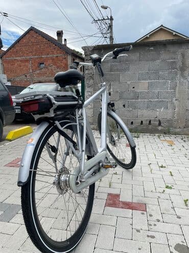 bicikli sa prednjim i zadnjim amortizerima: Električni bicikl u srebrnoj boji. Poseduje crno sedište i bateriju — 1