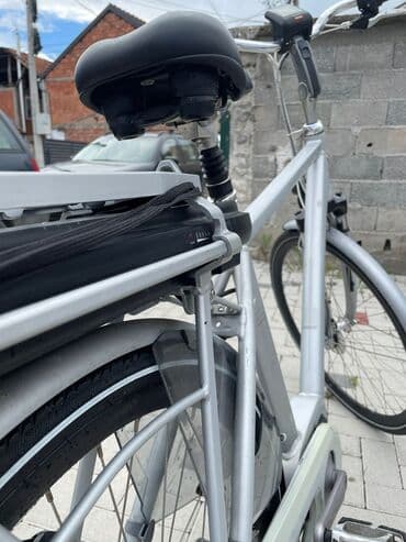 bicikli sa prednjim i zadnjim amortizerima: Električni bicikl u srebrnoj boji. Poseduje crno sedište i bateriju — 4