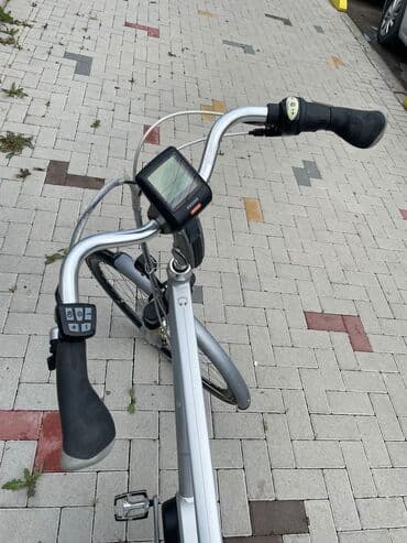 bicikli sa prednjim i zadnjim amortizerima: Električni bicikl u srebrnoj boji. Poseduje crno sedište i bateriju — 6