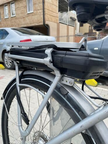 bicikli sa prednjim i zadnjim amortizerima: Električni bicikl u srebrnoj boji. Poseduje crno sedište i bateriju — 2