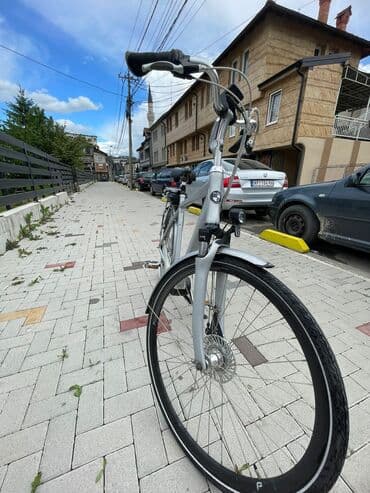 bicikli sa prednjim i zadnjim amortizerima: Električni bicikl u srebrnoj boji. Poseduje crno sedište i bateriju — 3