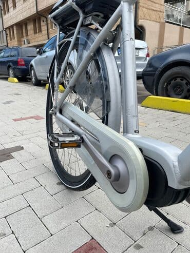 bicikli sa prednjim i zadnjim amortizerima: Električni bicikl u srebrnoj boji. Poseduje crno sedište i bateriju — 7